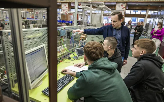 Uczniowie siedzący przy stanowisku dydaktycznym