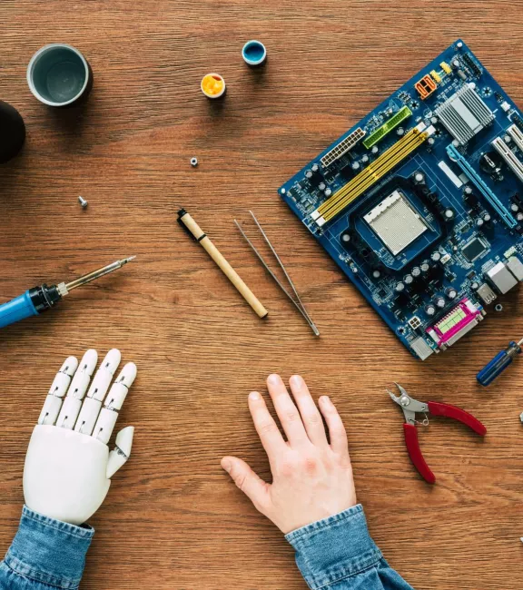 Przycięty obraz mężczyzny z protezą ręki siedzącego przy stole z instrumentami - pl.depositphotos.com